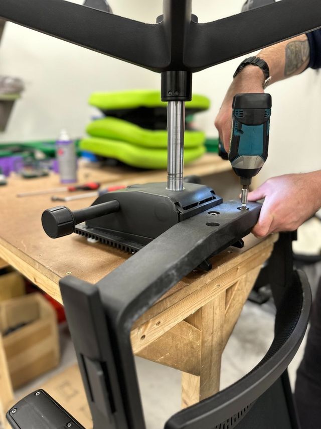 A new mechanism being fitted to a chair base with a drill