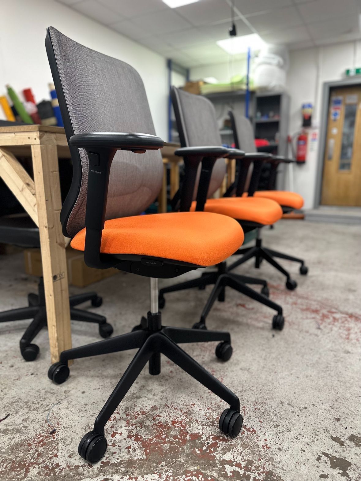 Refurbished task chairs with new orange seat fabric in the Coggin SOS workshop