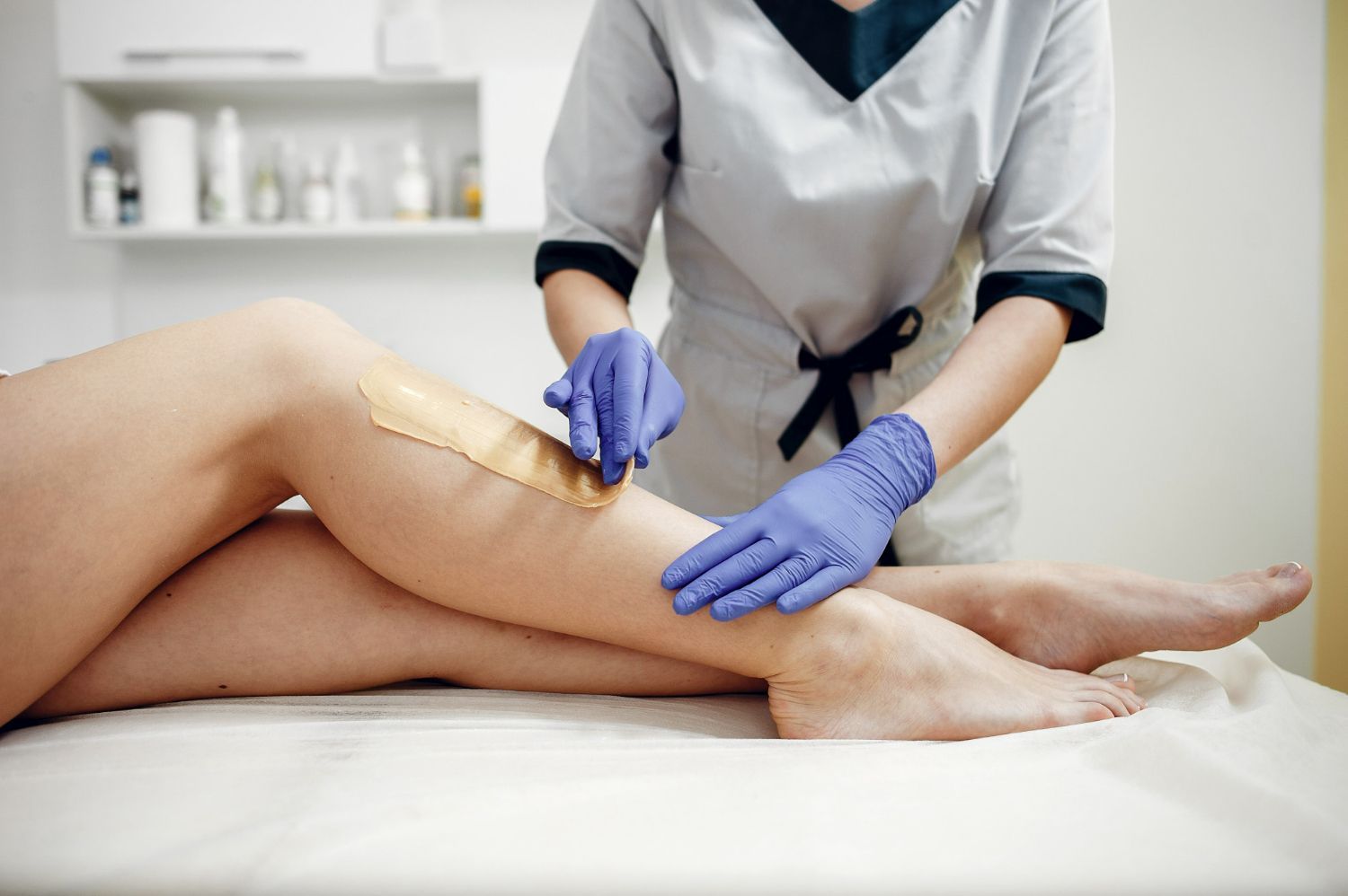 A woman is getting her legs waxed in a beauty salon.