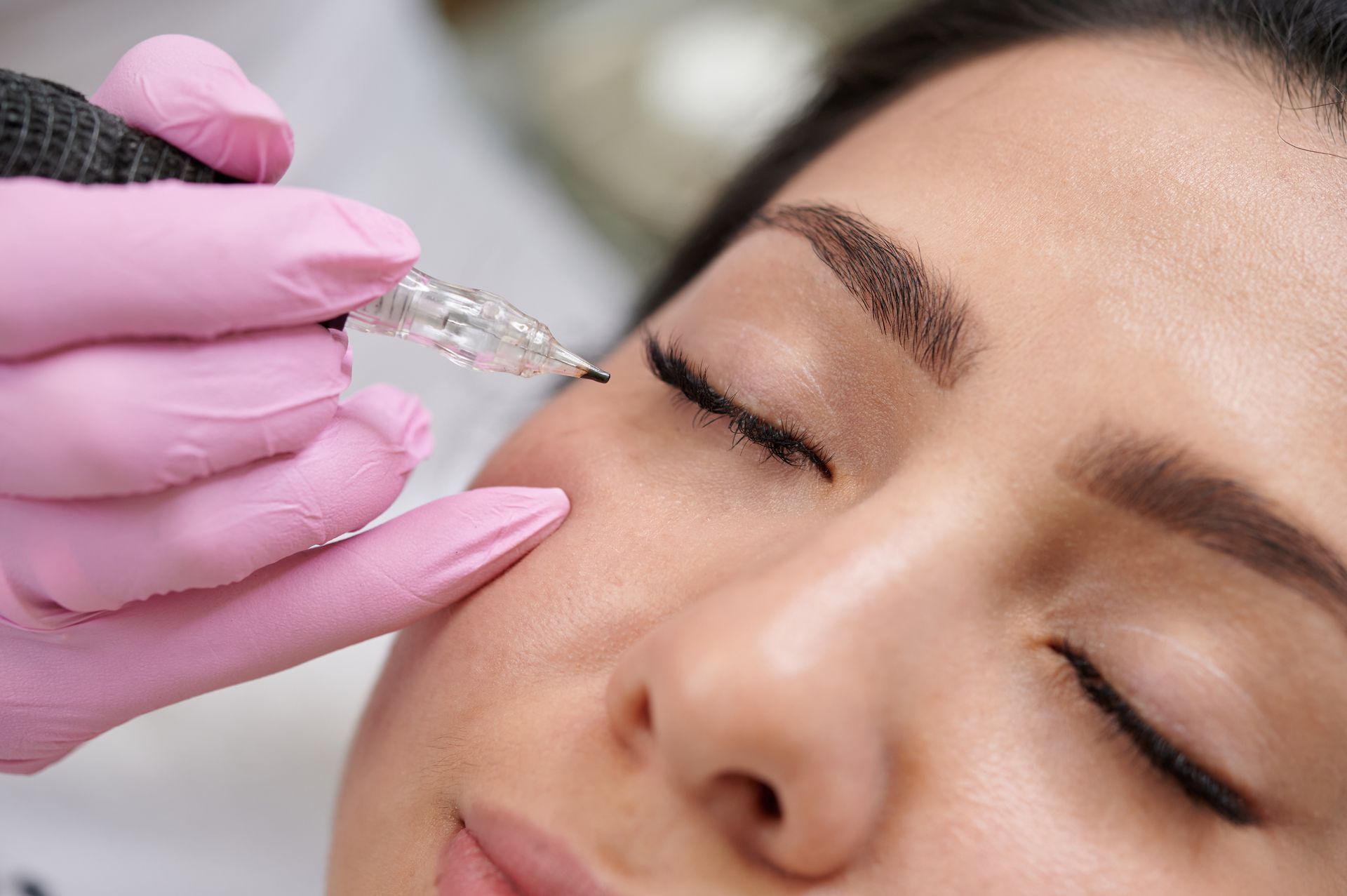 A woman is getting a tattoo on her eyebrows.