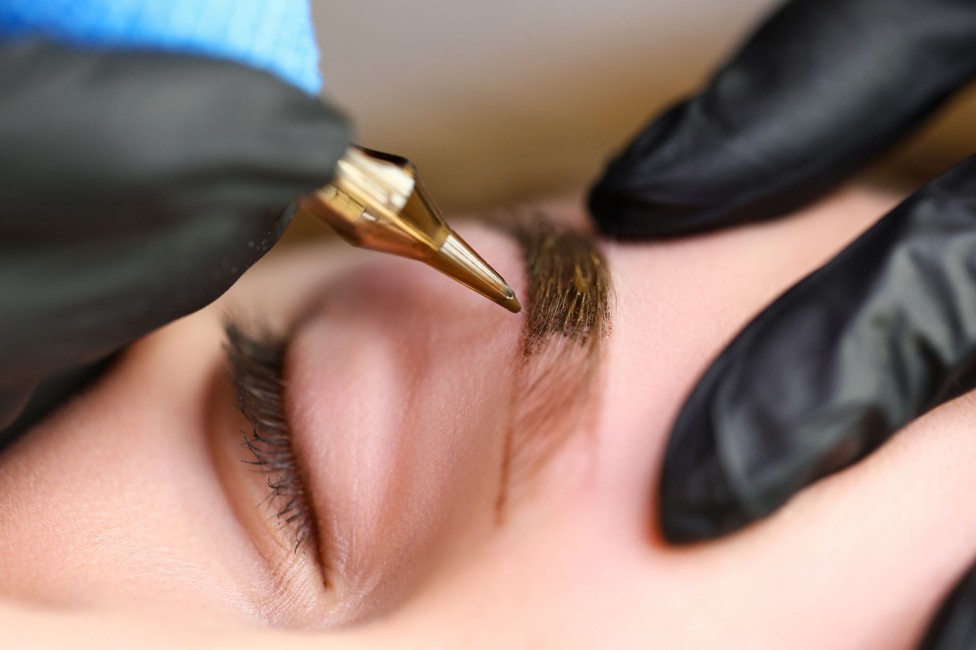 A woman is getting a permanent makeup tattoo on her eyebrows.