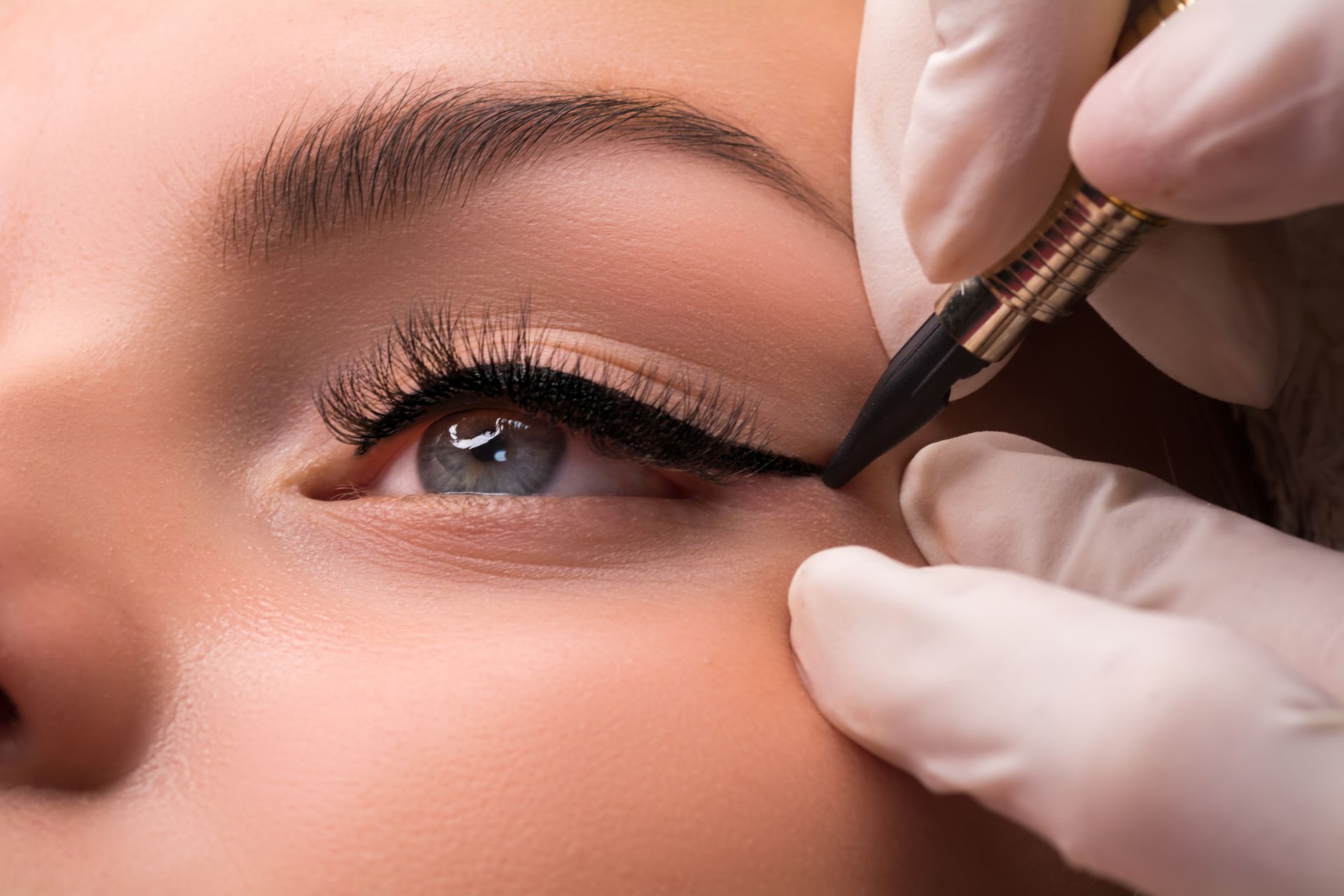 A close up of a person applying eyeliner to a woman 's eye.