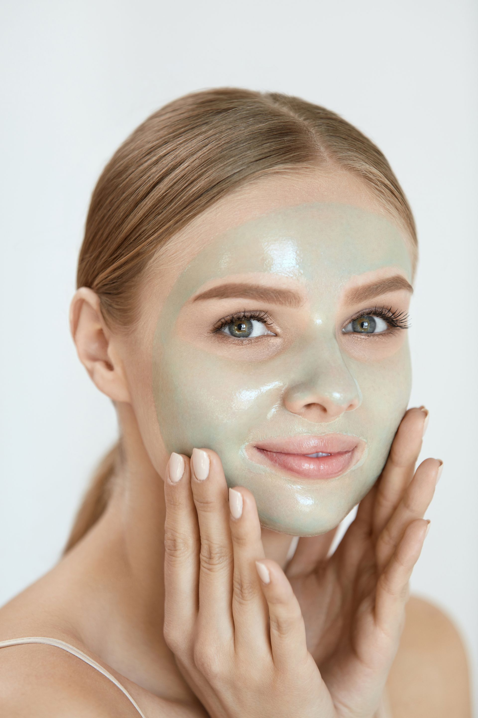 A woman is wearing a green clay mask on her face.