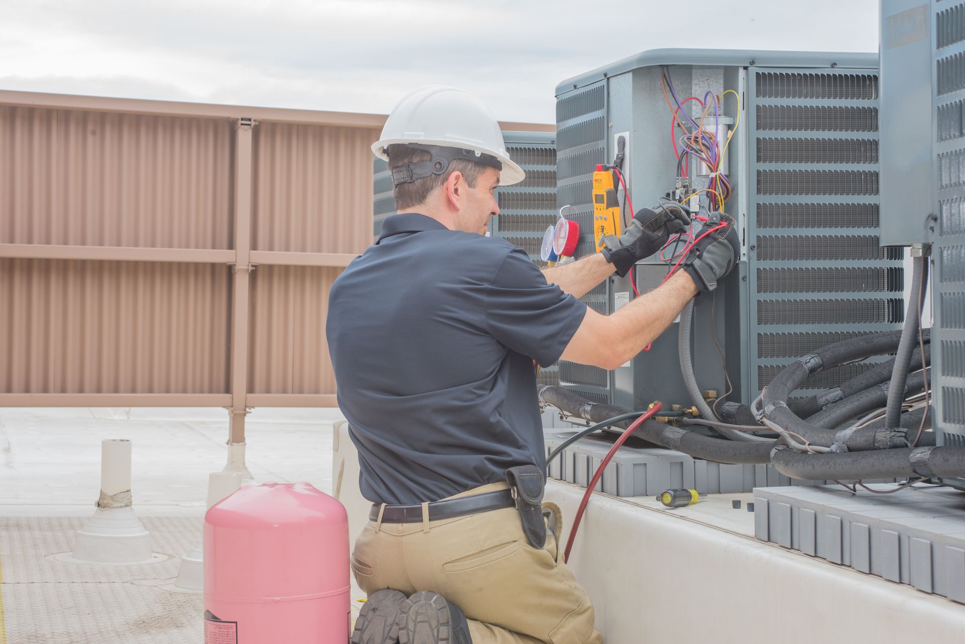 HVAC technician inspecting the outdoor AC condenser for proper operation. HVAC technician inspecting the outdoor AC condenser for proper operation.