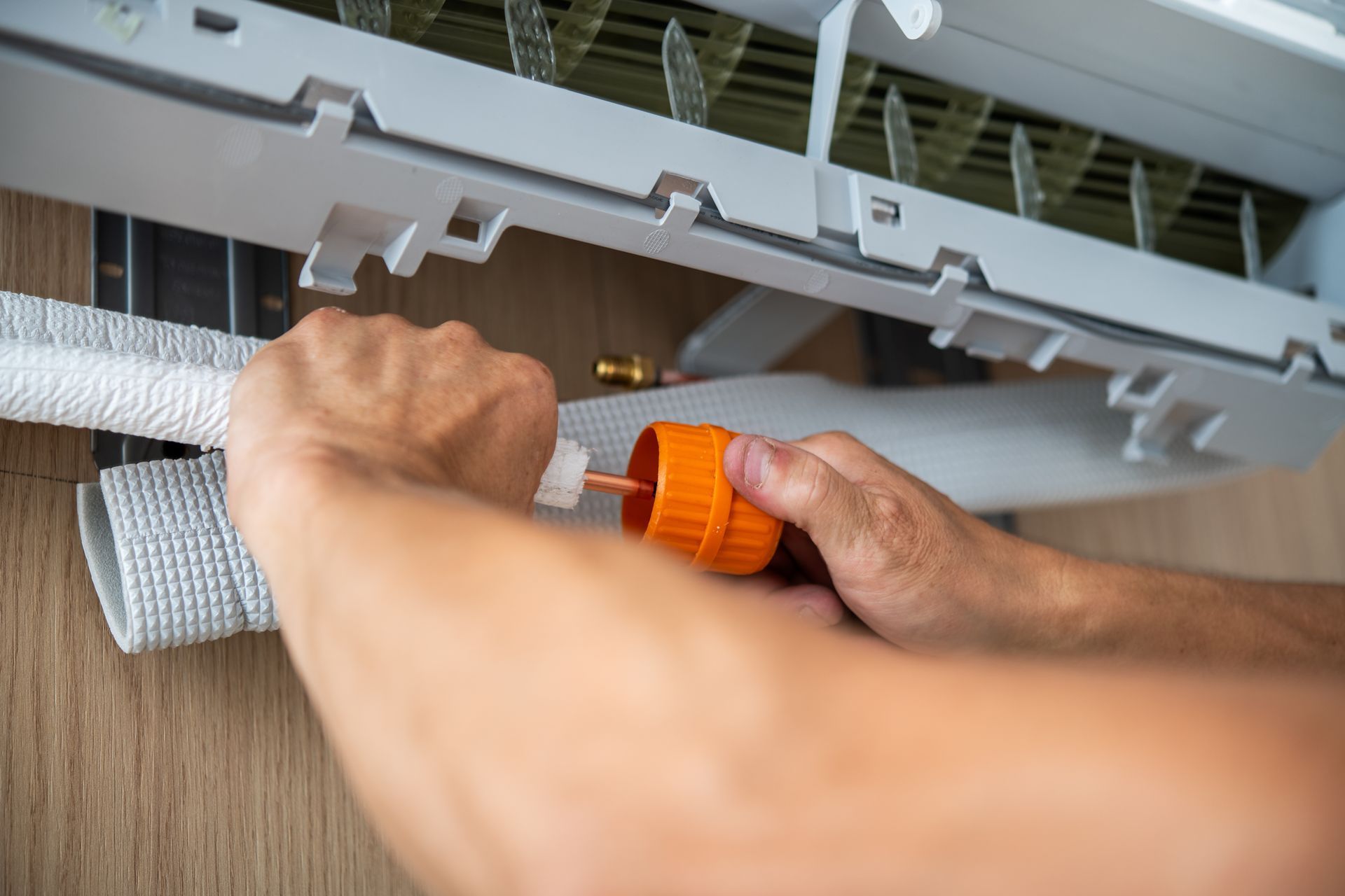 A man is installing an indoor air conditioning unit piping.