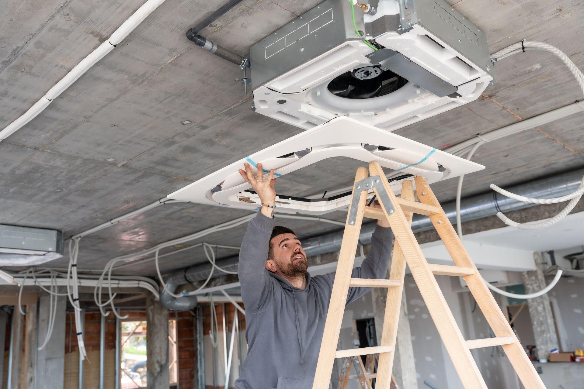 Technician installing rooftop air conditioning unit on construction ceiling. Technician installing rooftop air conditioning unit on construction ceiling.