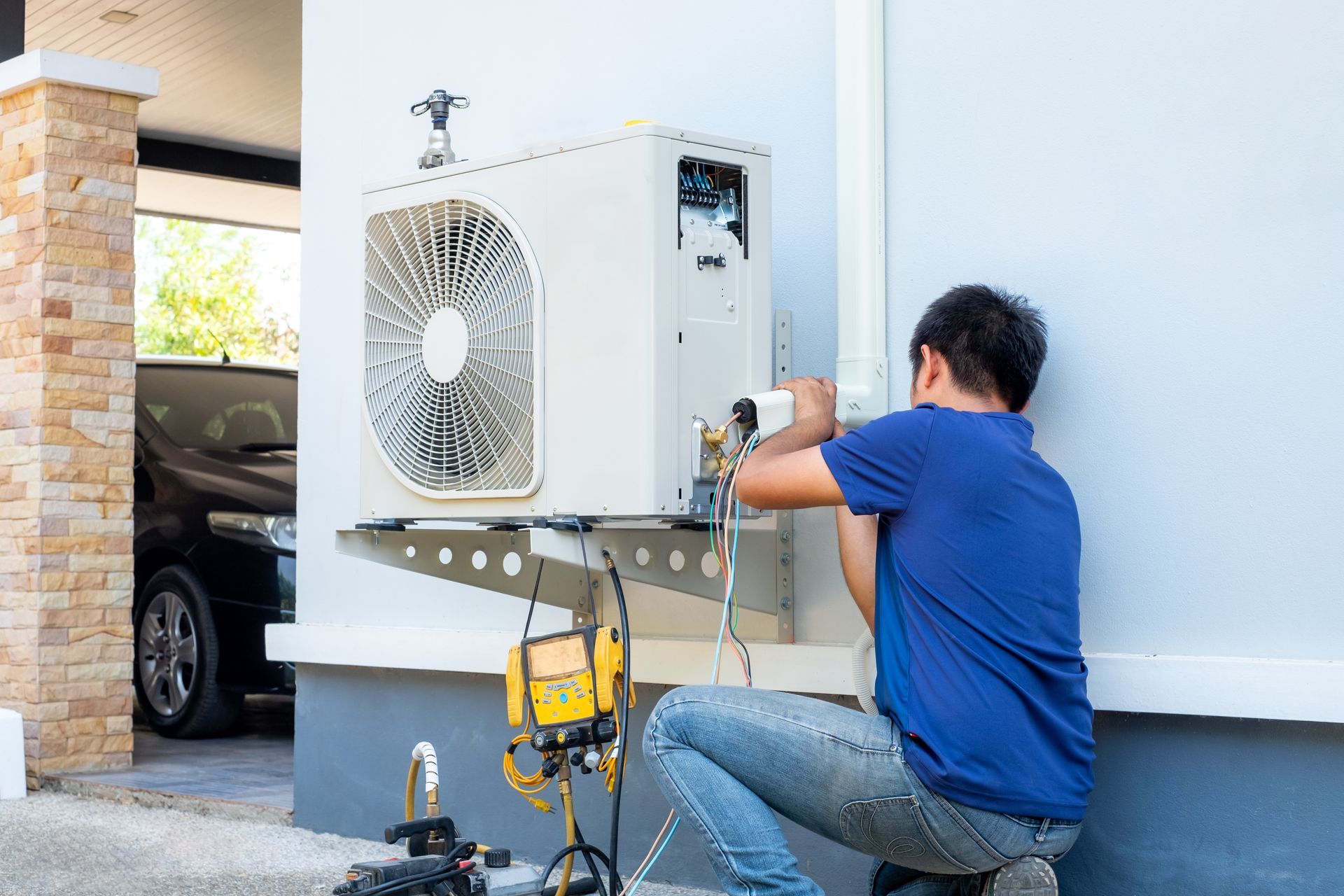 Technician installing or repairing an outdoor AC unit mounted on a house wall. Technician installing or repairing an outdoor AC unit mounted on a house wall.