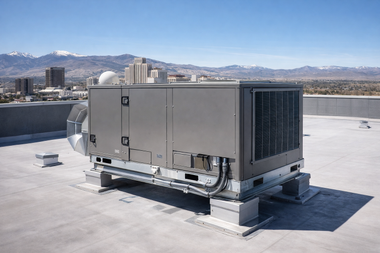 Rooftop industrial HVAC unit on a flat roof with city buildings and mountains in the background