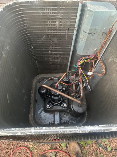 Open utility pit with coiled copper pipes and tangled wires at the bottom