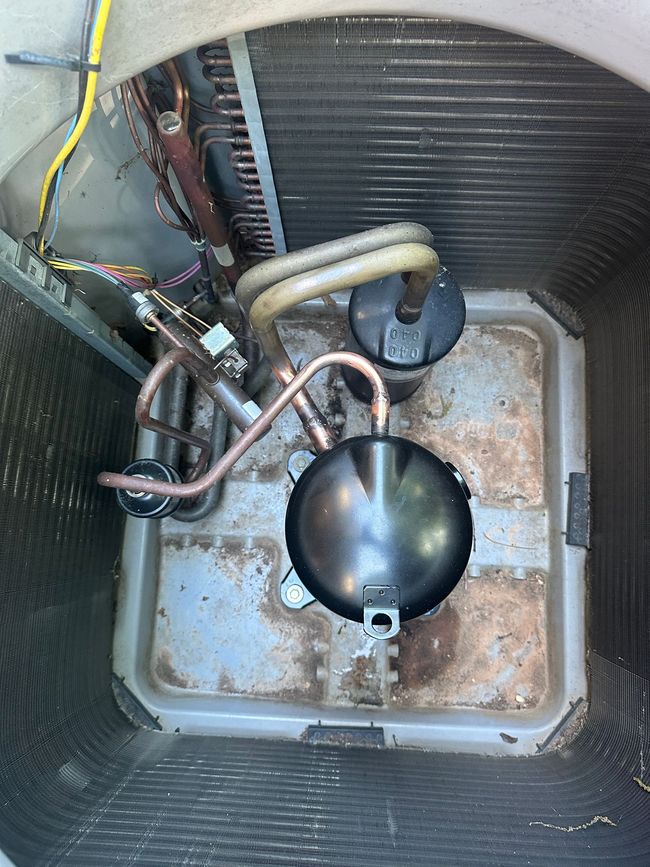 HVAC condensate pump inside a unit, with copper tubing, wiring, and a black float chamber.
