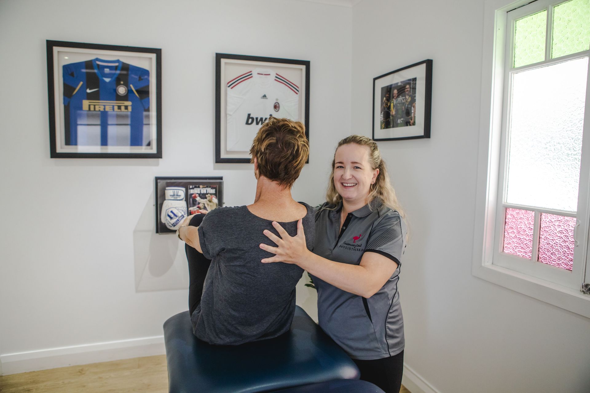 Physiotherapist assisting a person with a back stretch in an office setting.