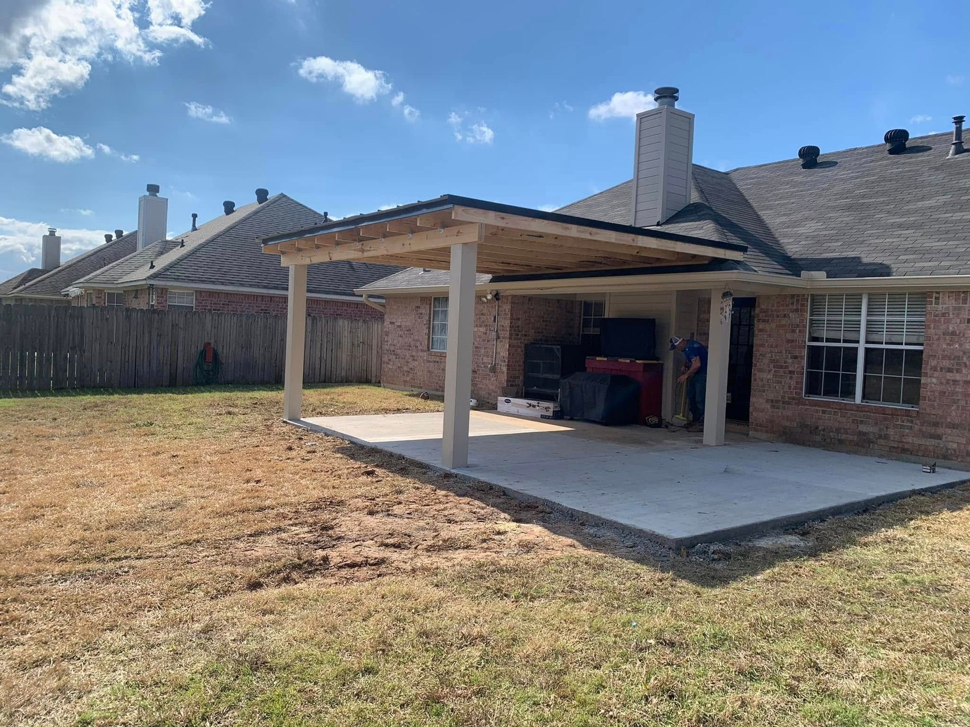 A brick house with a covered patio in the backyard.