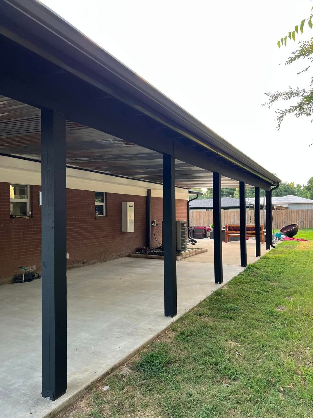 A long covered porch with a brick house in the background.