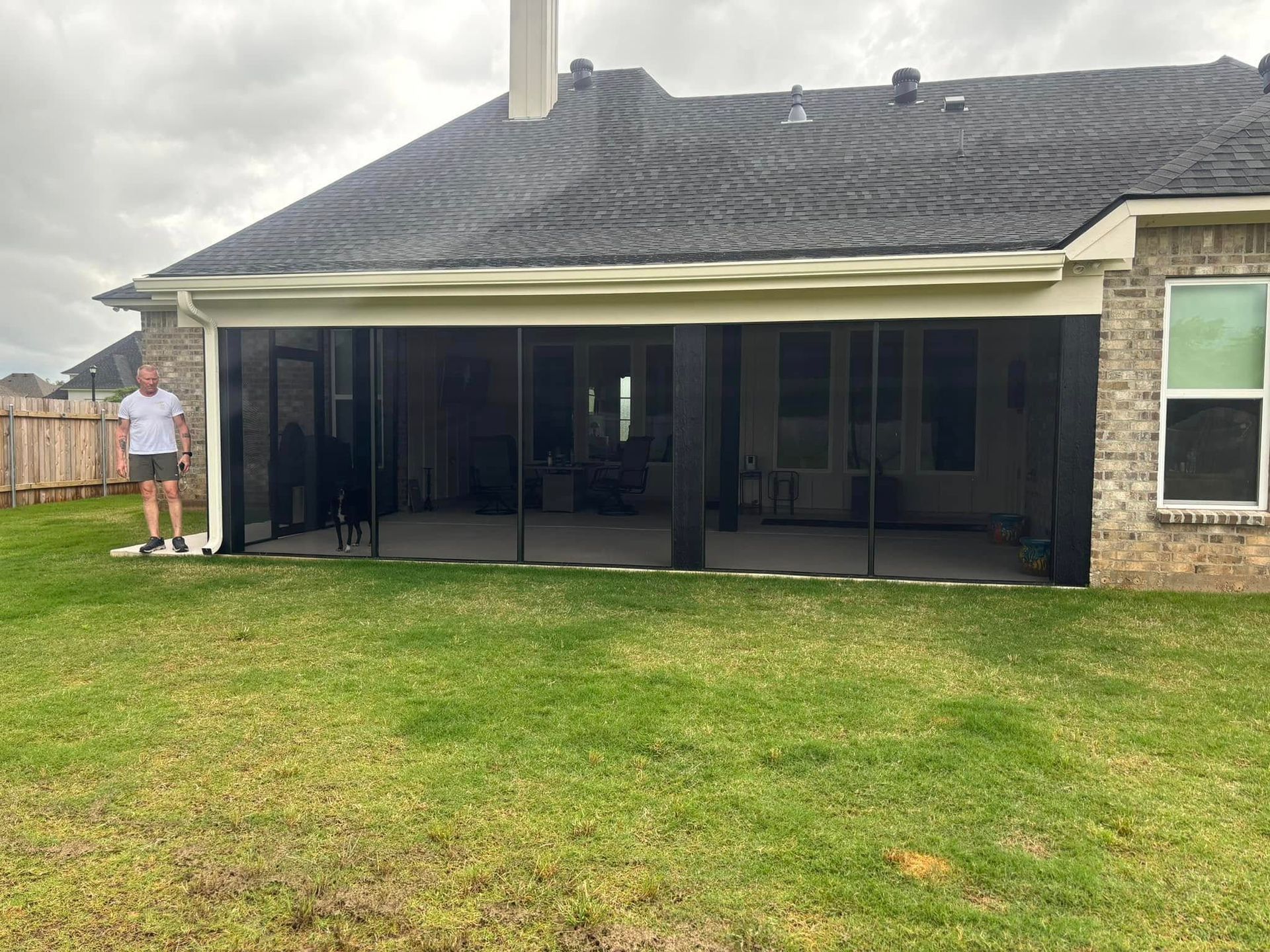 A man is standing in front of a screened in porch.