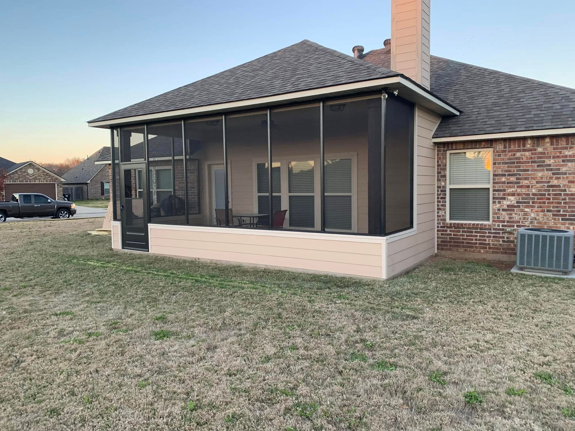 A house with a screened in porch and a truck parked in front of it.