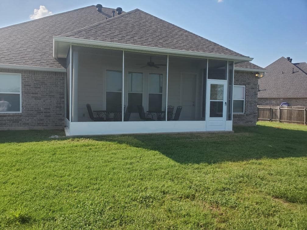 There is a screened in porch in the backyard of a house.
