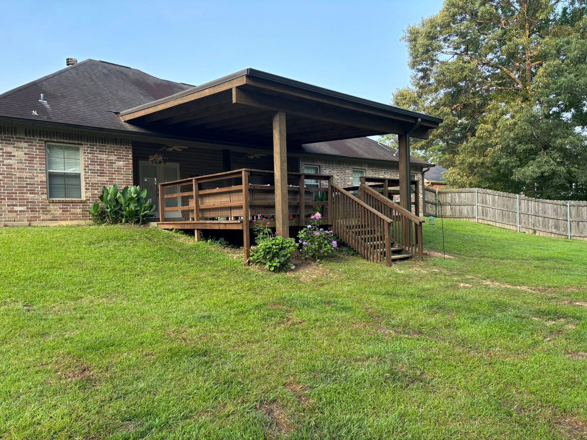 A house with a covered deck and stairs in the backyard.