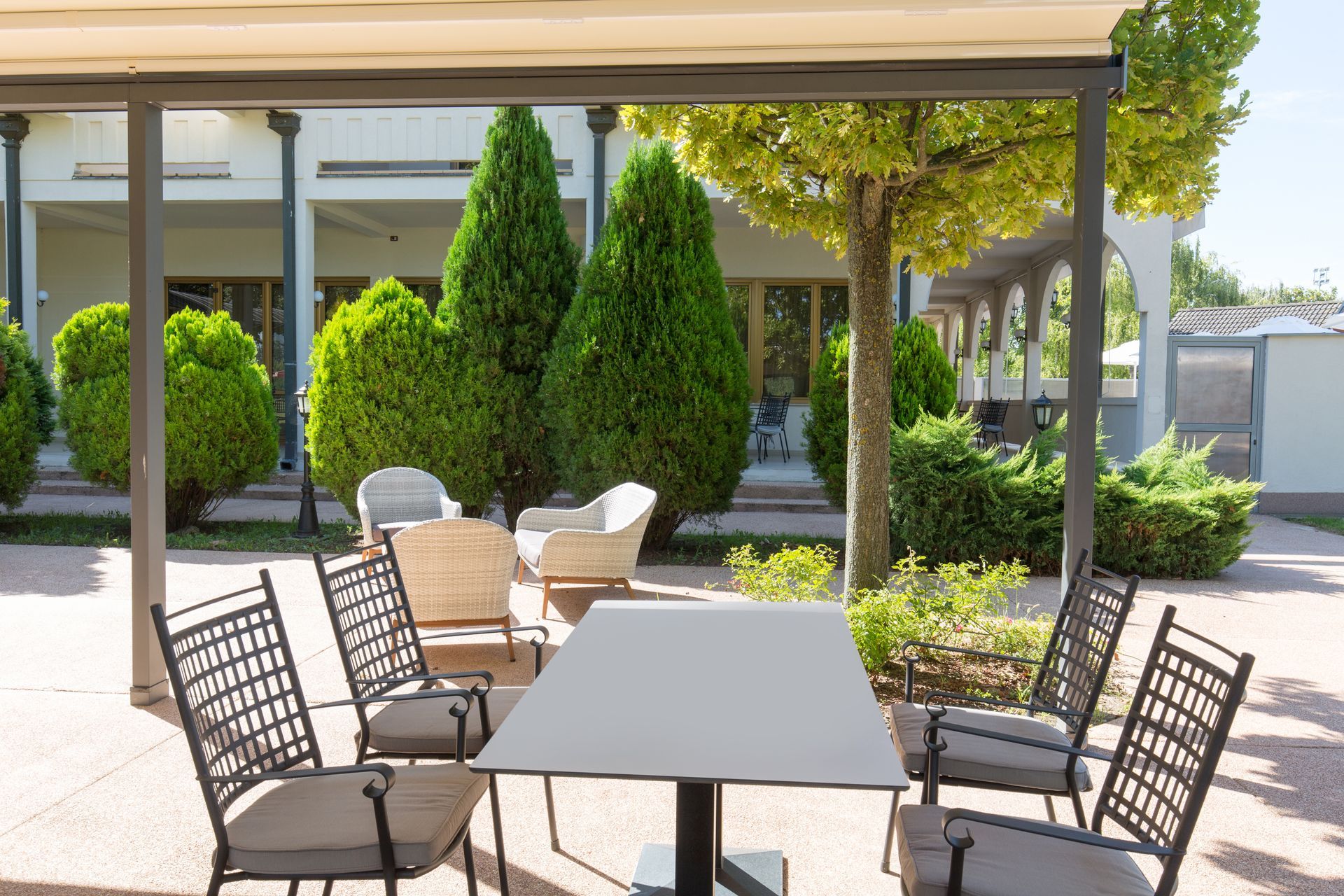 Covered patio with outdoor dining set overlooking vibrant backyard garden and greenery.