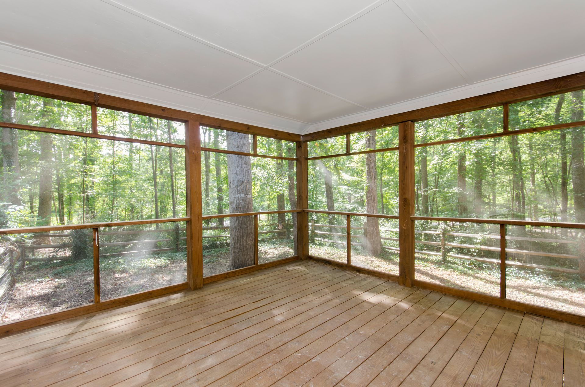 Screen enclosure in a wooden deck in a natural setting with wood floors.
