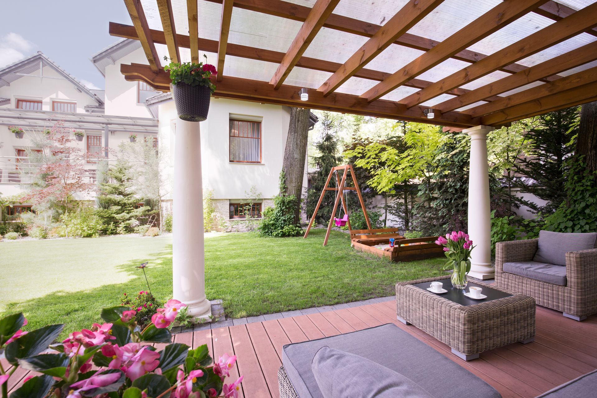 Covered patio overlooking lush backyard garden with vibrant flowers and greenery.