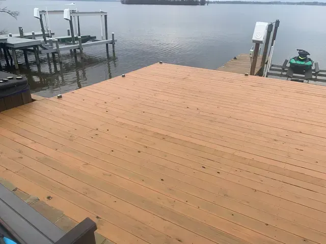 Wooden dock deck extending over calm water beside a foggy lakeside marina