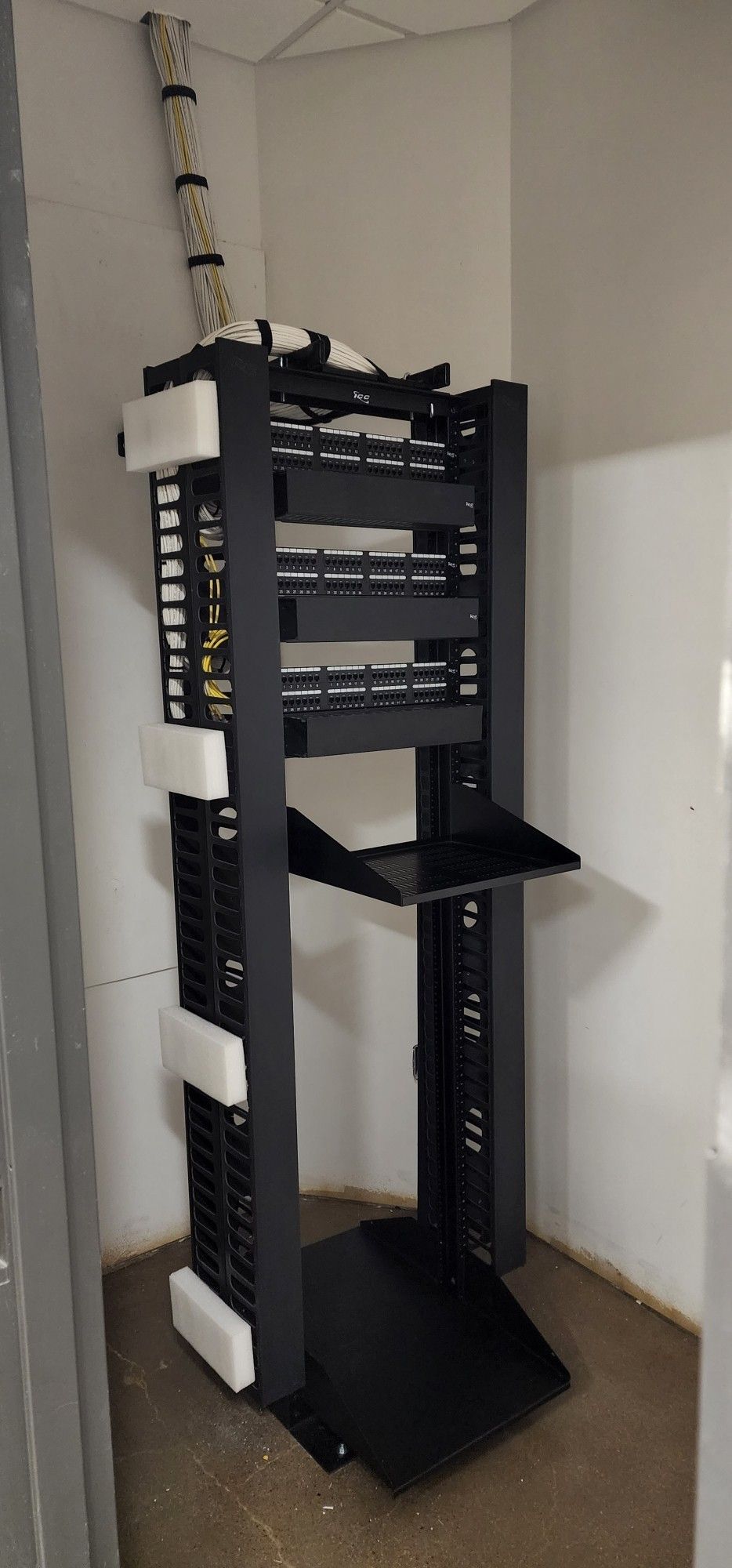 A server rack is sitting in a corner of a room.
