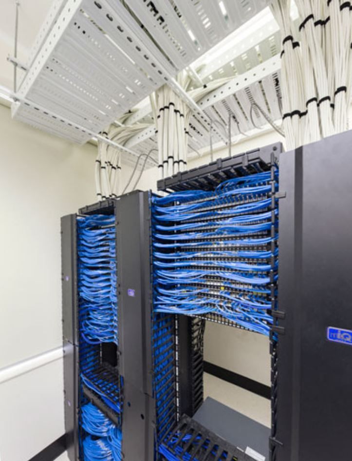 A server room with a lot of blue wires hanging from the ceiling.