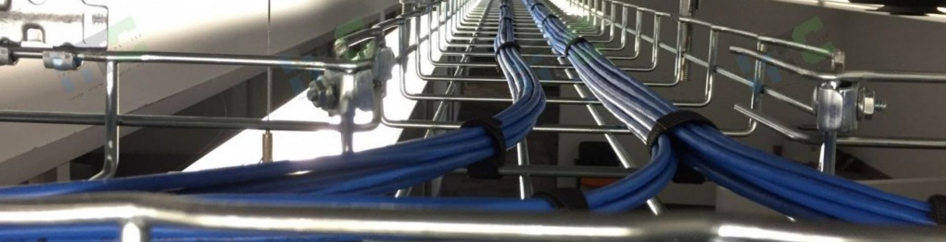 A bunch of blue wires are hanging from a metal railing.