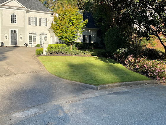 A large white house with a large driveway and a lush green lawn.
