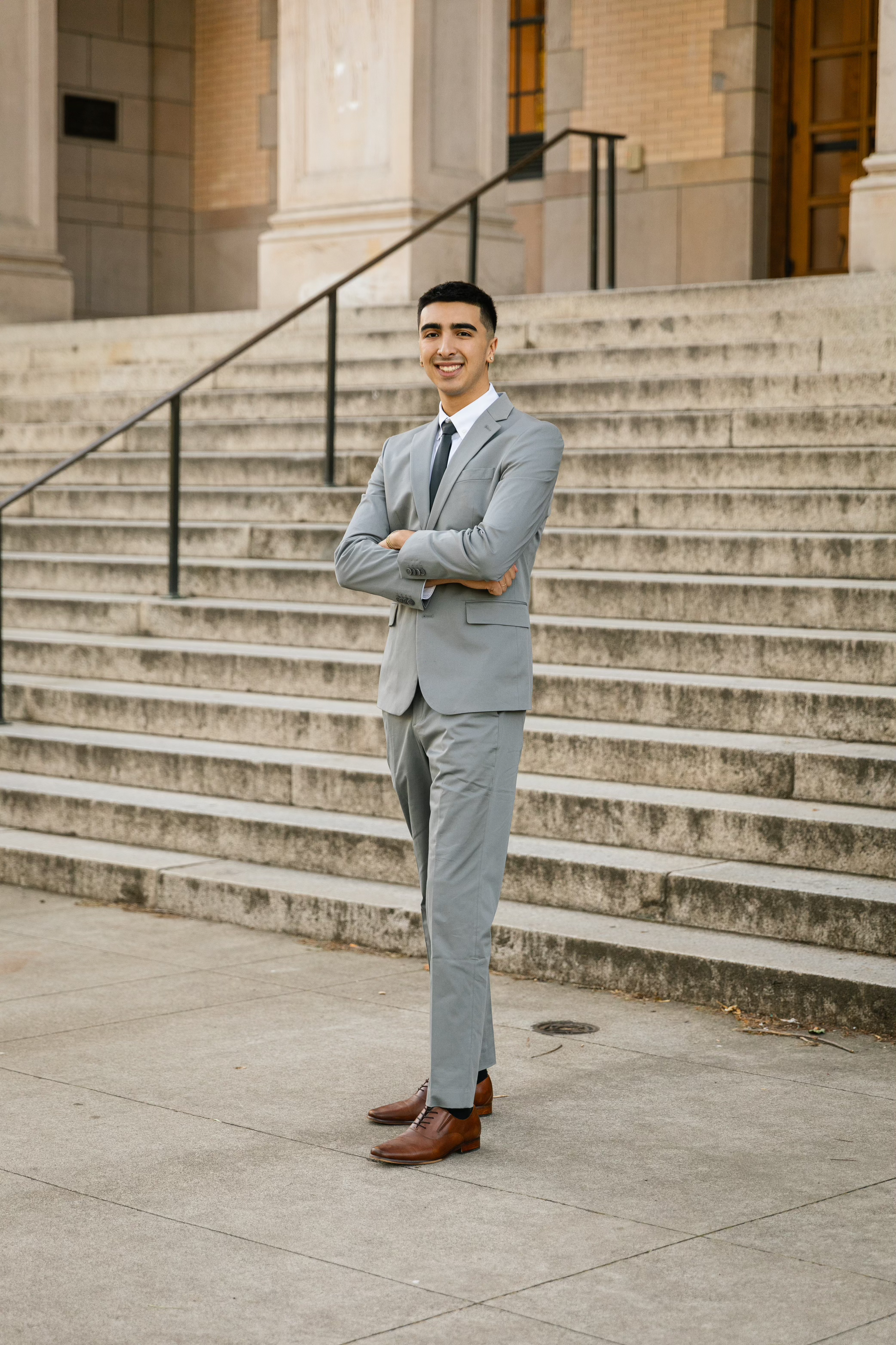 A man in a suit and tie is standing in front of a set of stairs.