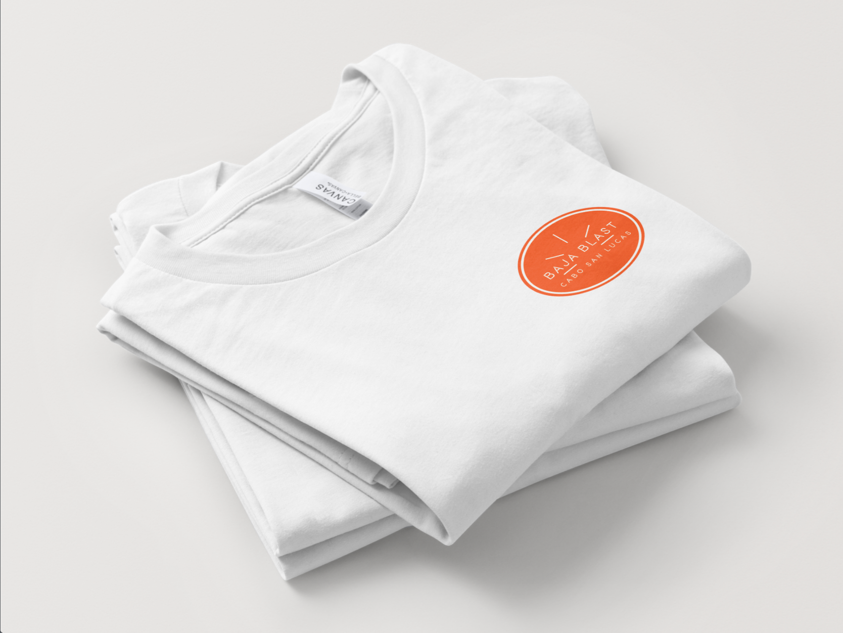 Folded white t-shirts with an orange circular logo, stacked on a white surface.