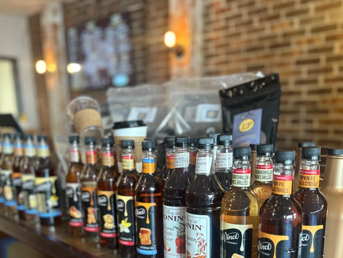 A row of bottles of syrup are lined up on a counter.