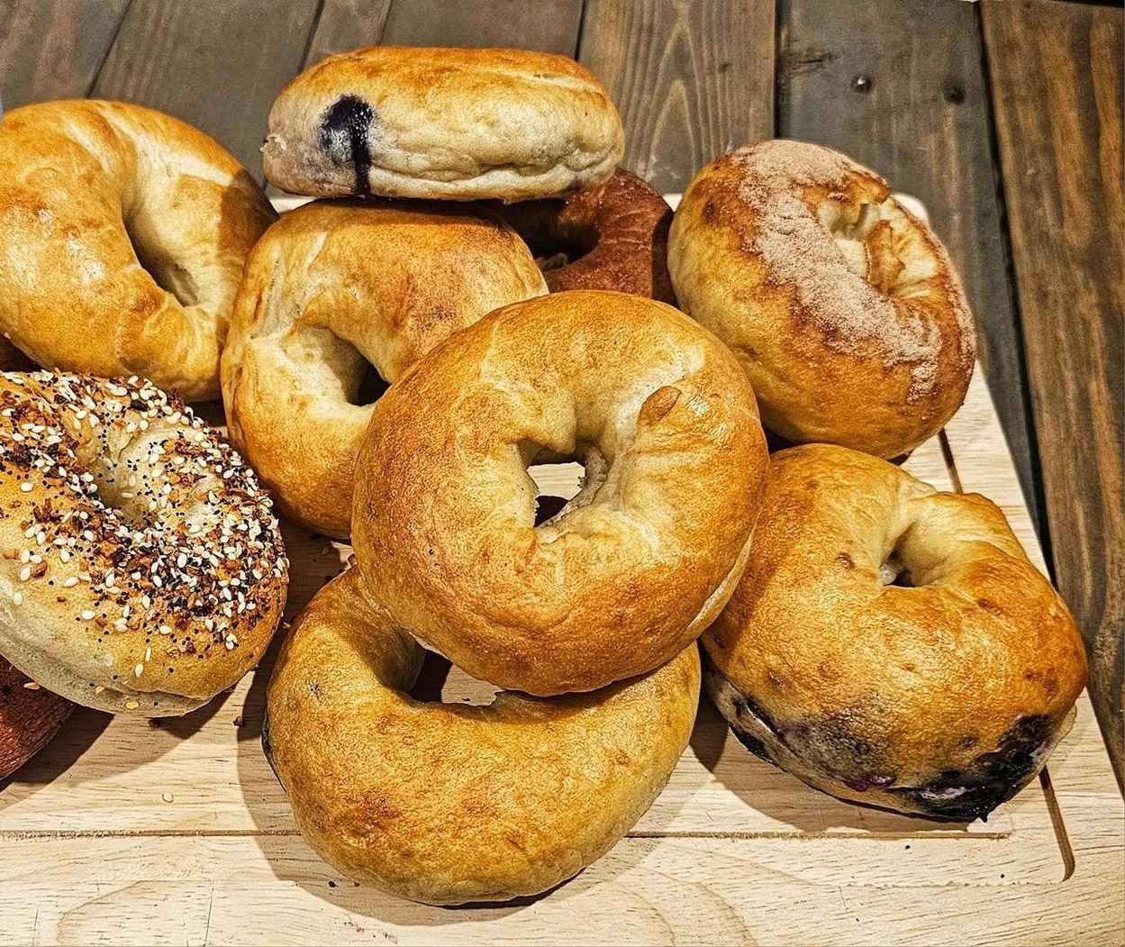 A wooden cutting board topped with a variety of bagels.