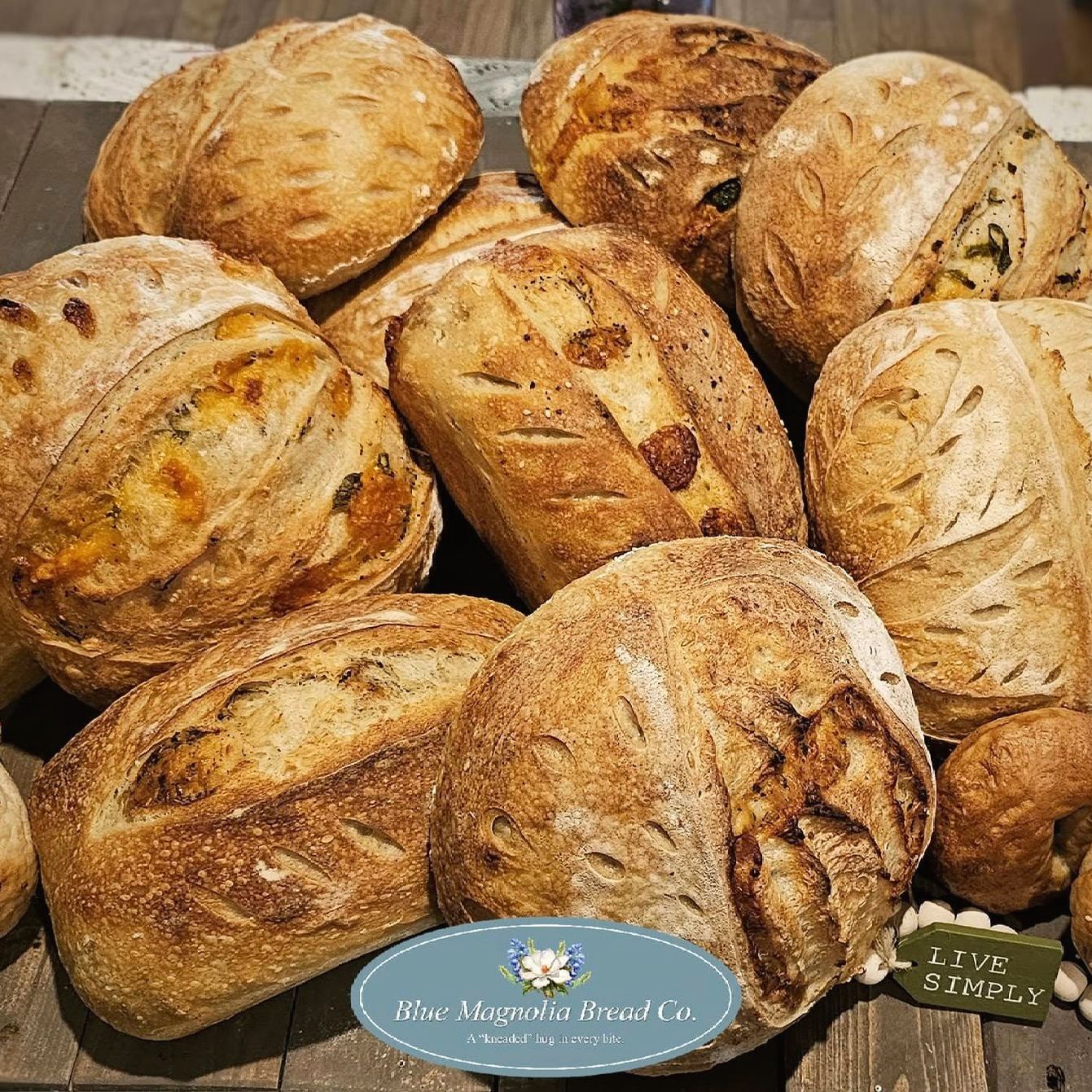 A bunch of loaves of bread are sitting on a wooden table.