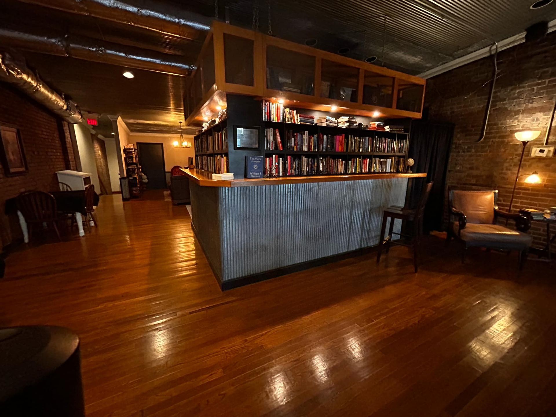A large room with hardwood floors and a bar in the middle of it.