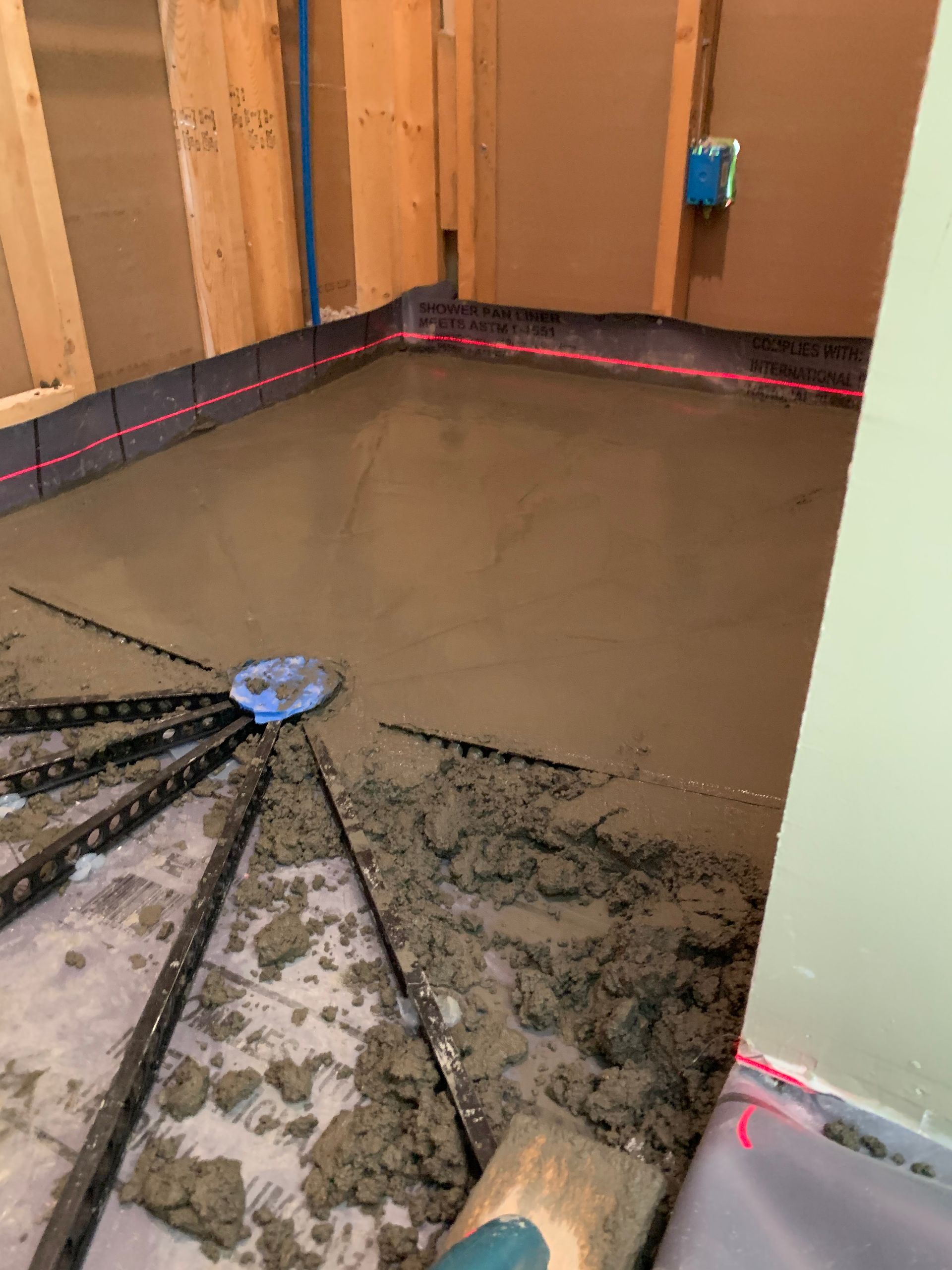 A person is laying concrete on the floor in a room.