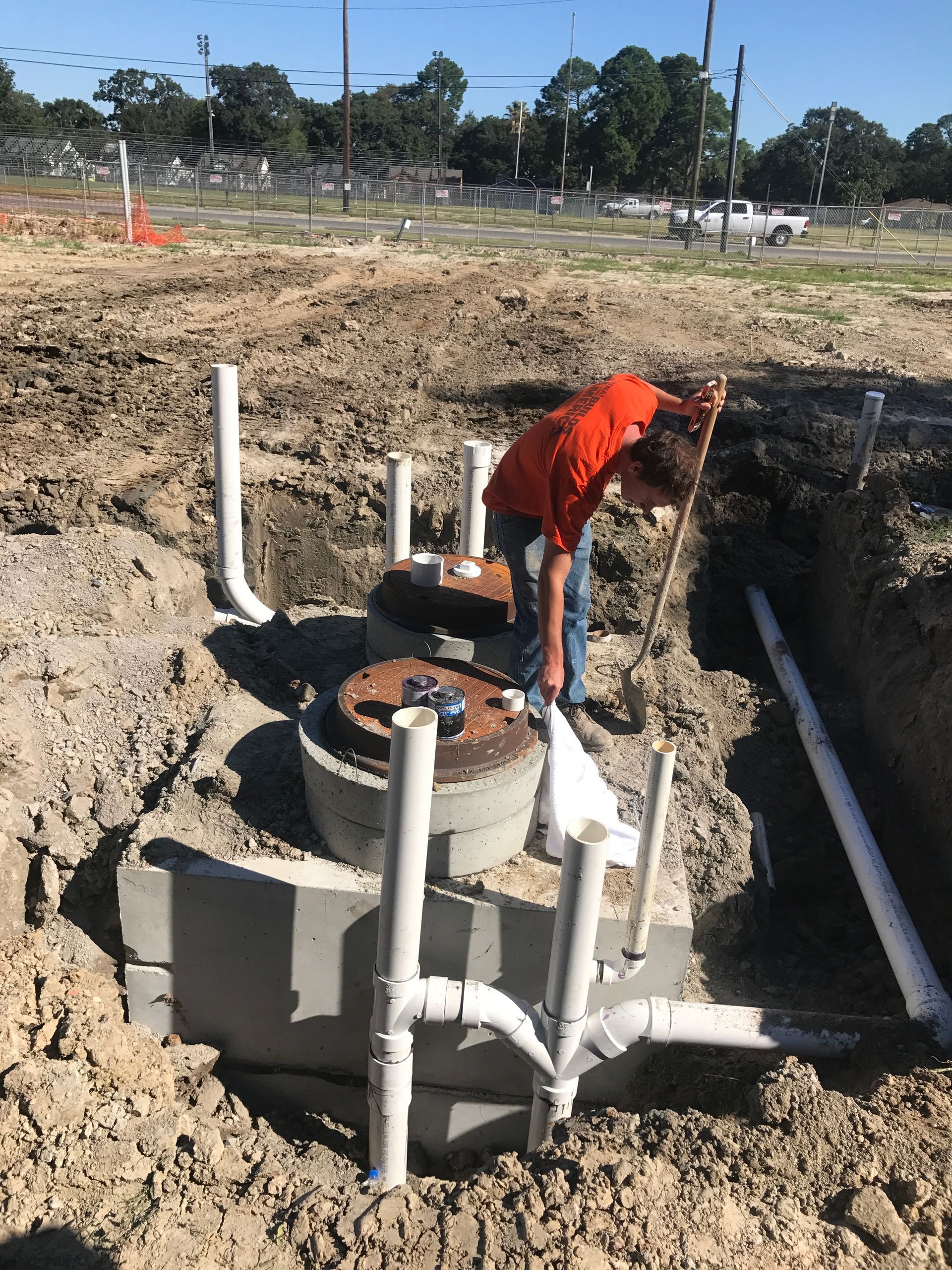 A man is working on a septic tank in a dirt field.
