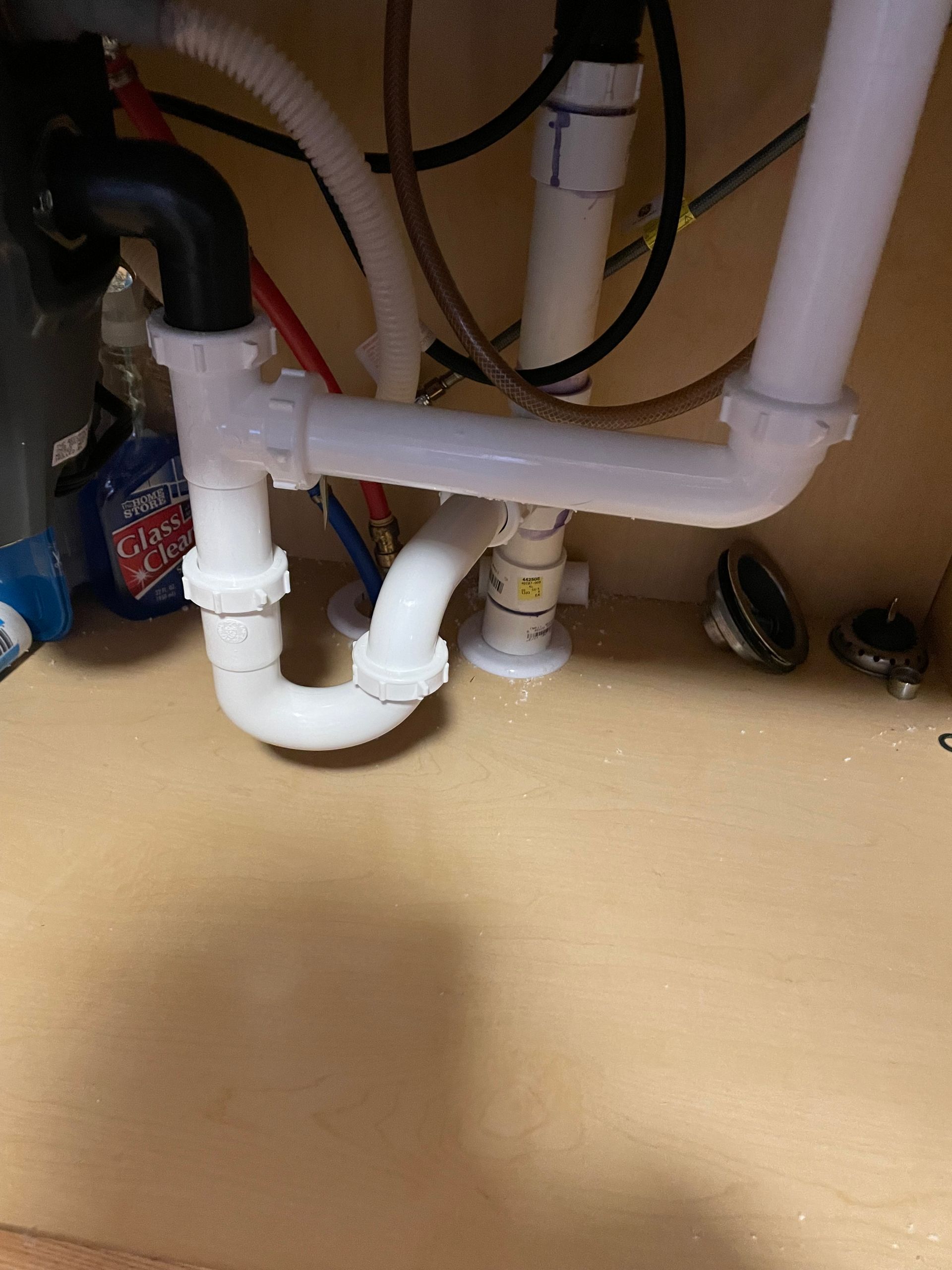 A kitchen sink with a lot of pipes underneath it