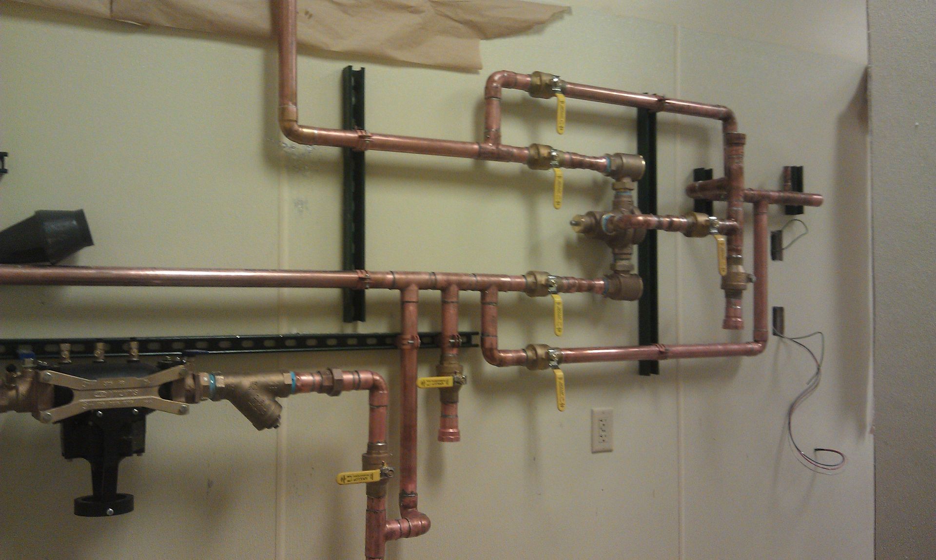 A bunch of copper pipes are hanging on a wall