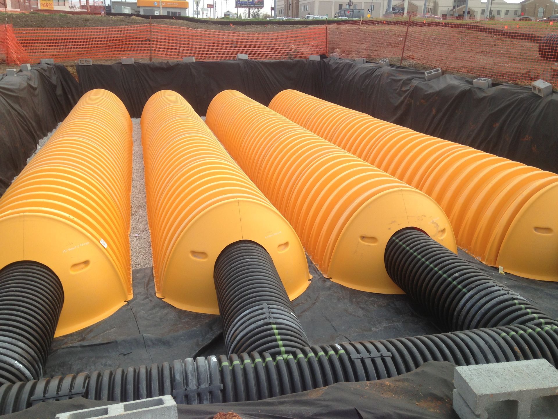 A bunch of yellow pipes are laying in the dirt