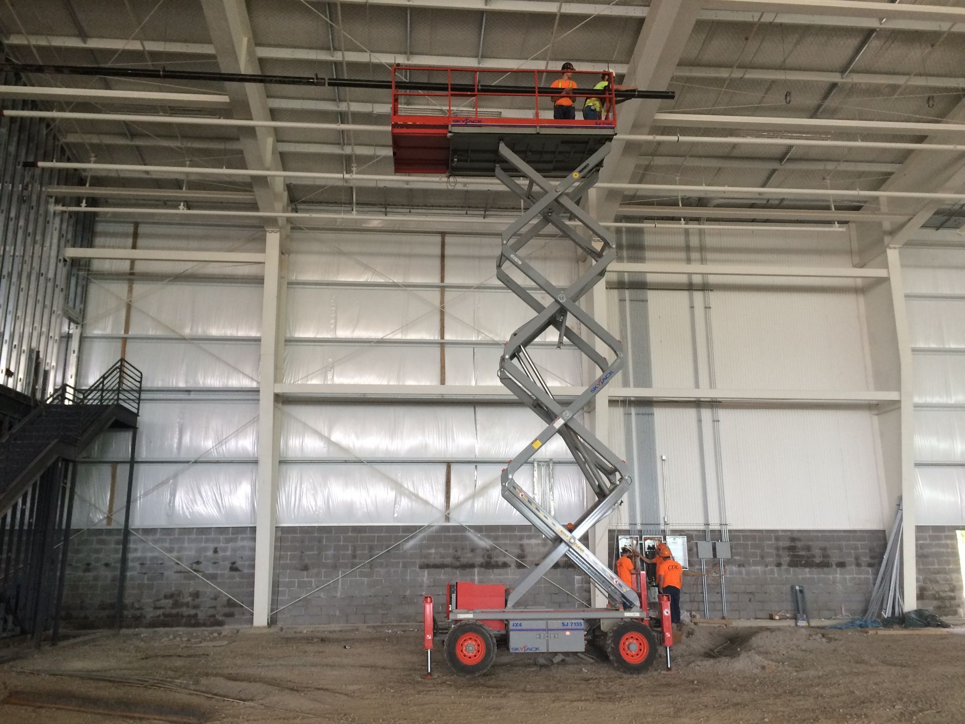 A man is standing on a scissor lift in an empty building.
