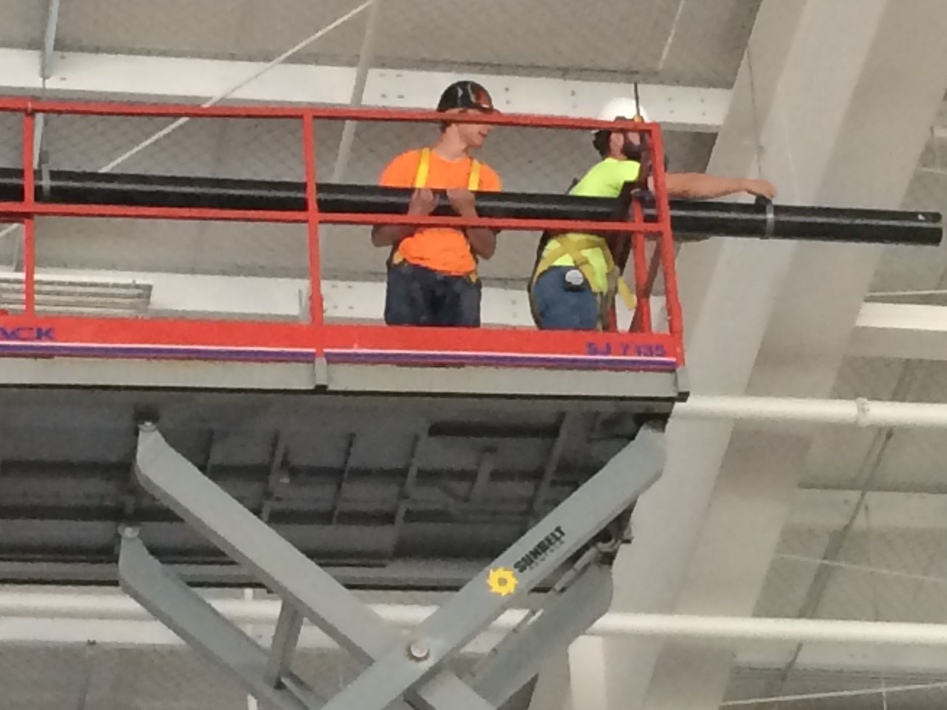 Two men are working on a scissor lift that says ' simpson ' on it