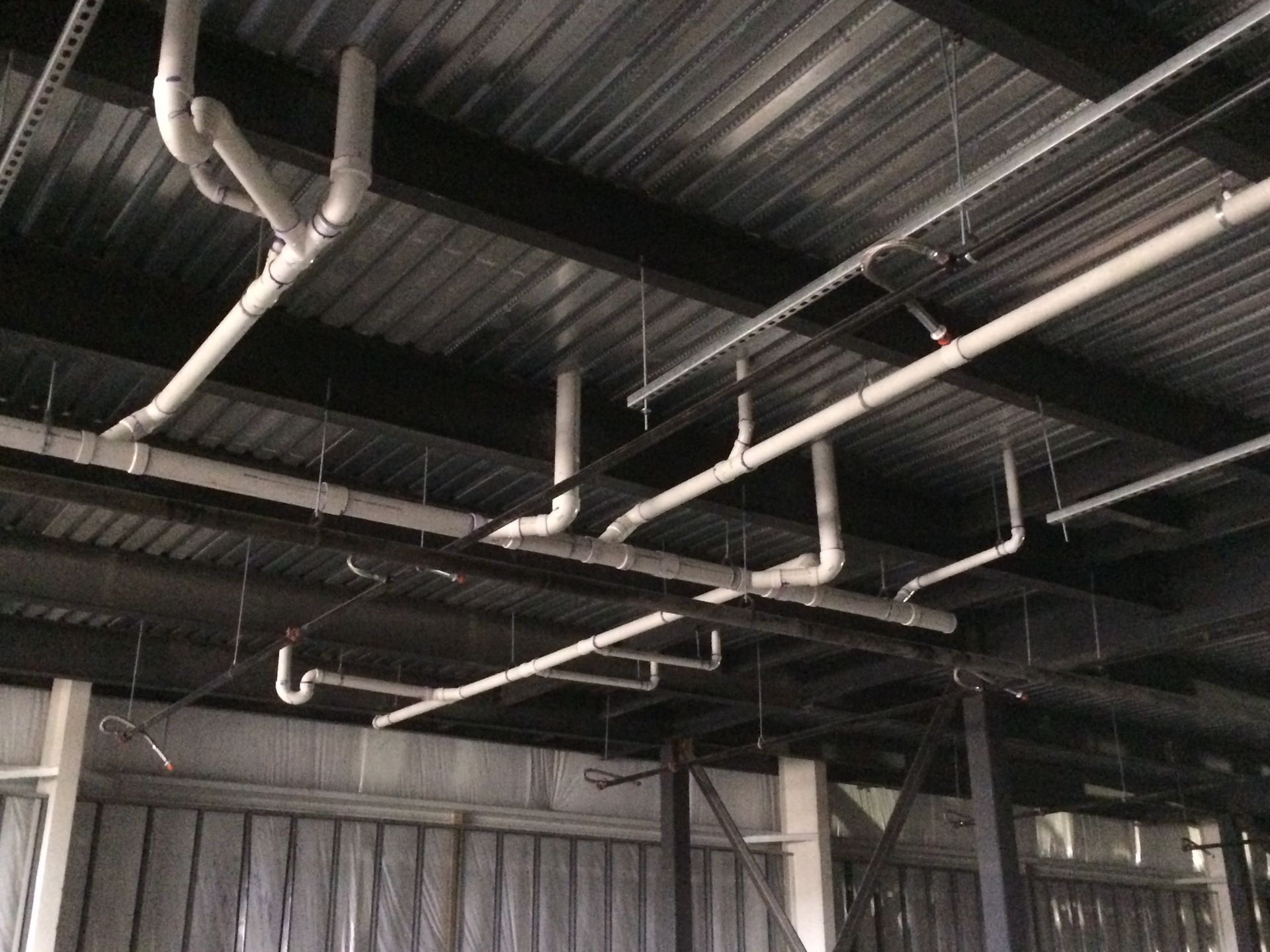 A bunch of pipes are hanging from the ceiling of a building