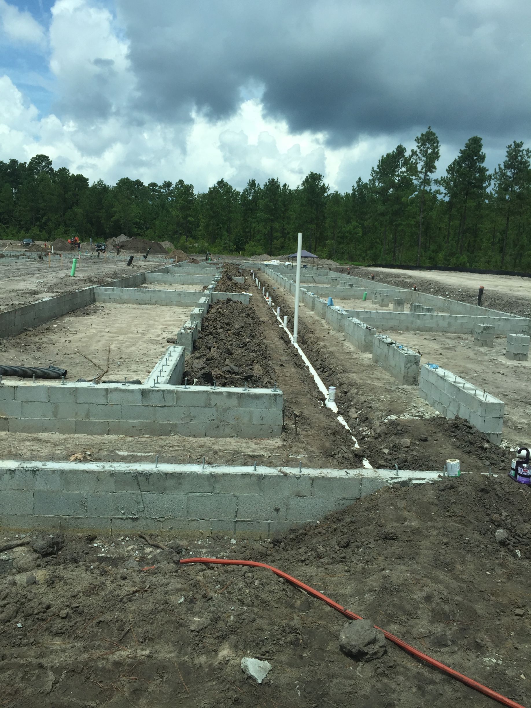 A construction site with a lot of dirt and trees in the background.