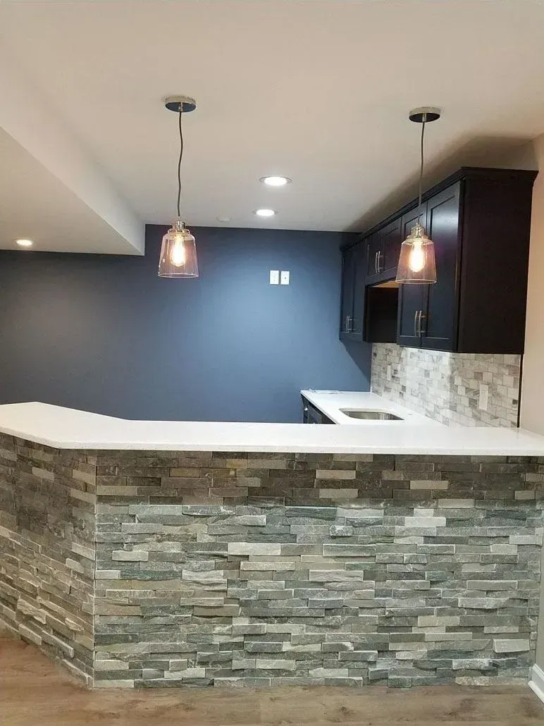 A kitchen with a stone counter top and a blue wall.