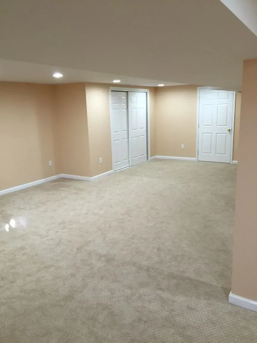 An empty basement with tan walls and tan carpet