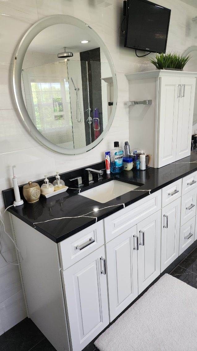 A bathroom with a sink , mirror and television.