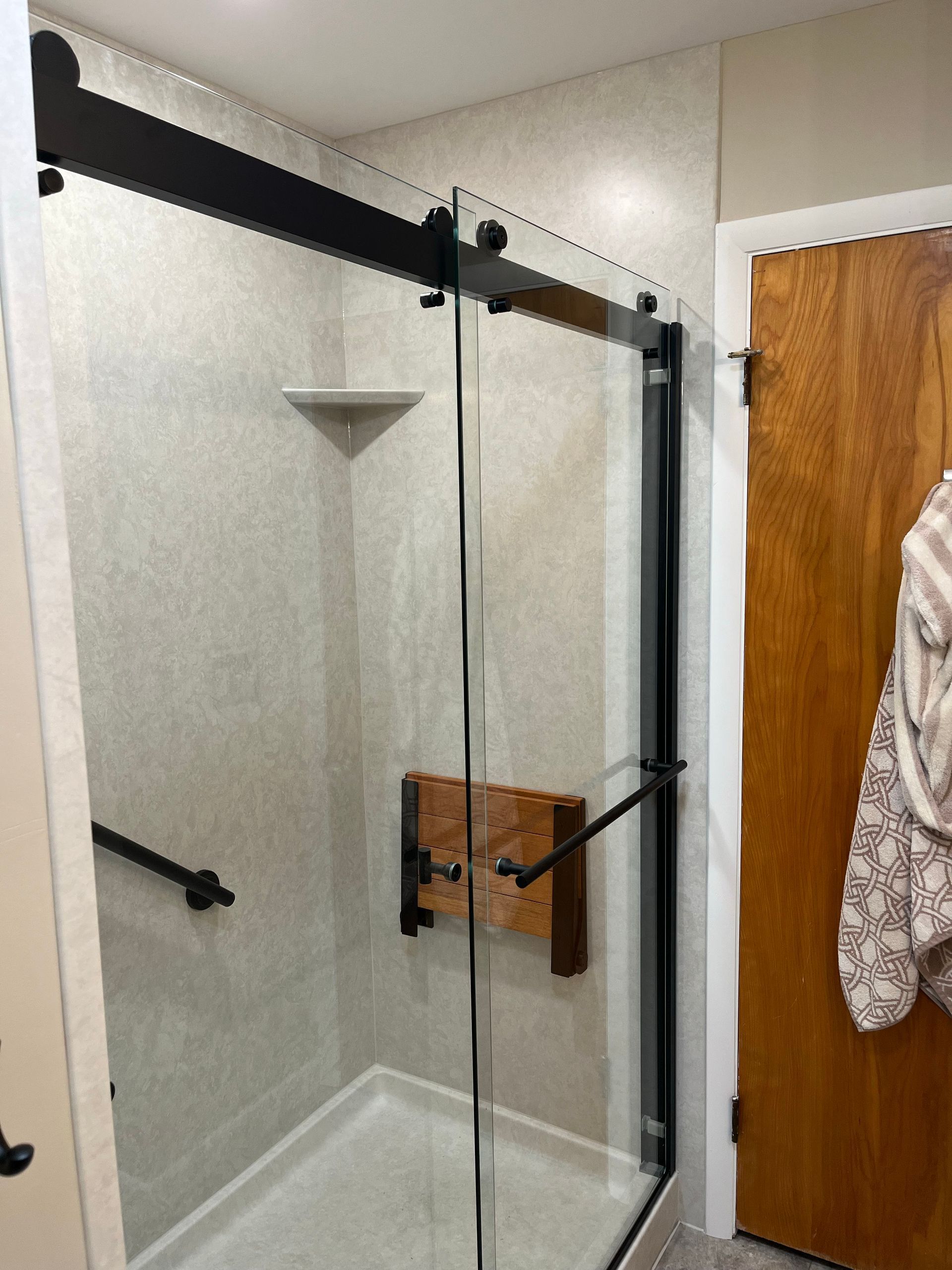 A bathroom with a sliding glass shower door and a wooden door.