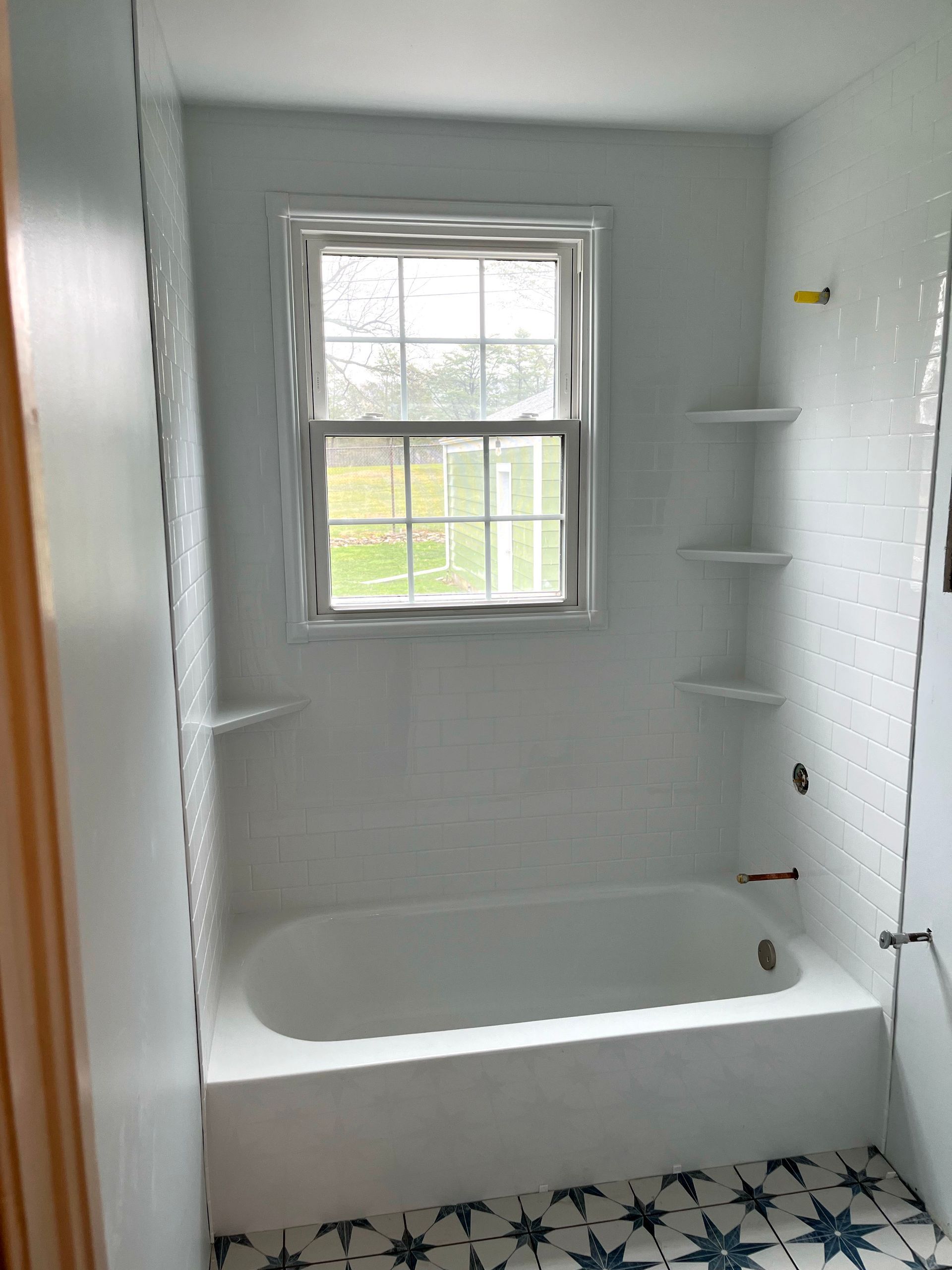 A bathroom with a bathtub and a window.