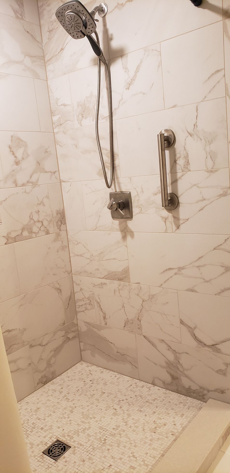 A shower with a hand rail and a shower head in a bathroom.